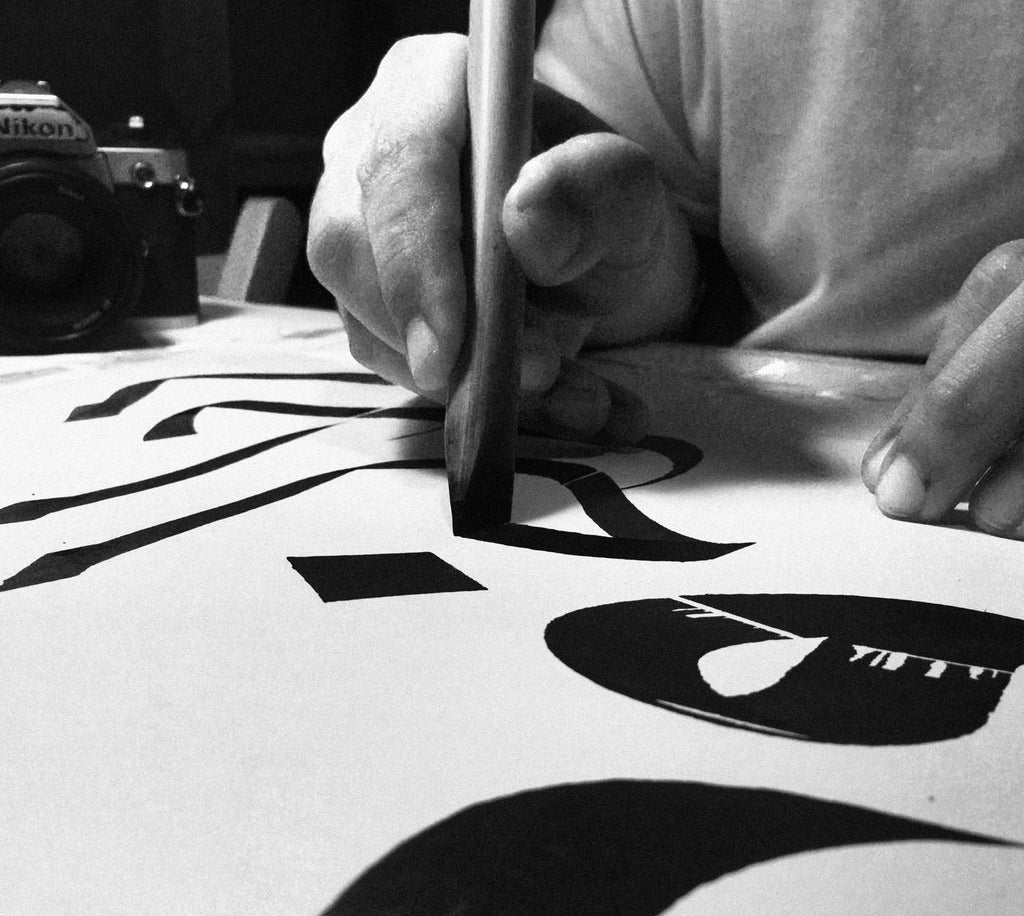 An Arabic calligraphy khat practitioner demonstrating writing a script using large bamboo pen.
