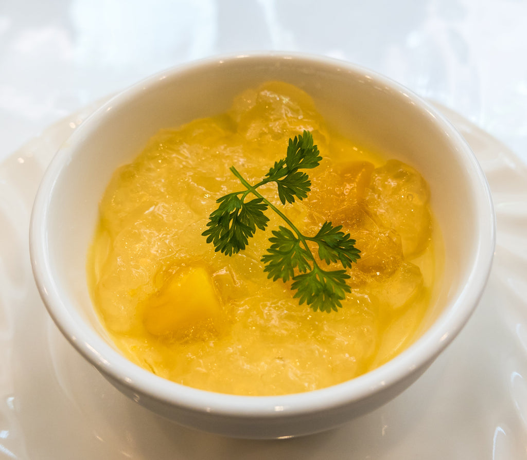 Mango pudding jelly in a white bowl garnished with parsley leaves.