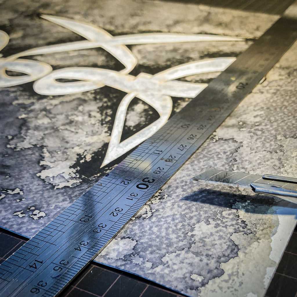 Knife and ruler to cut and trim a piece of Islamic calligraphy artwork to a finishing size.